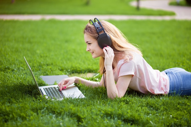 Girl in the Park working on a laptop with headphones