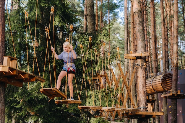 A girl passes an obstacle in a rope town A girl in a forest rope park