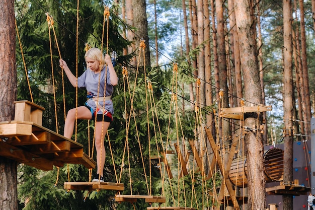 A girl passes an obstacle in a rope town A girl in a forest rope park