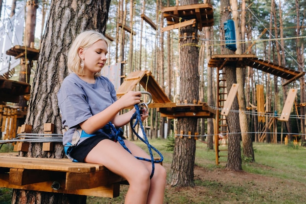 A girl passes an obstacle in a rope town A girl in a forest rope park