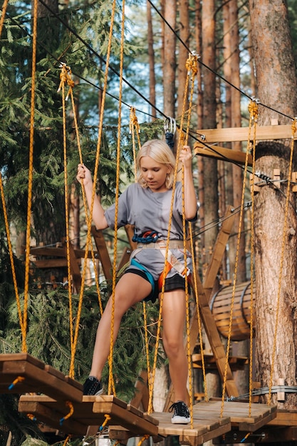 A girl passes an obstacle in a rope town A girl in a forest rope park