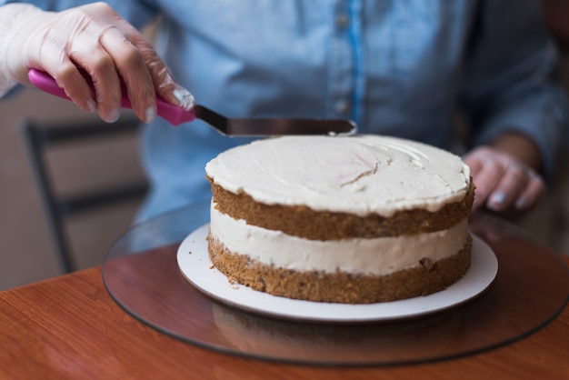 Girl Pastry Chef makes a wedding cake with his own hands and squeezes the cream on the cake layers