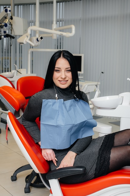 A girl patient of a dental clinic is sitting in a chair and smiling