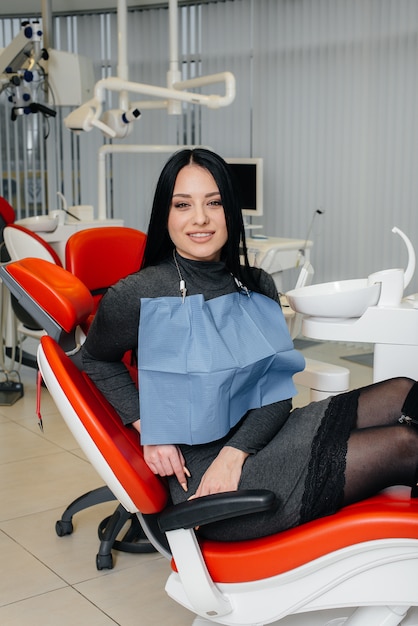 A girl patient of a dental clinic is sitting in a chair and smiling.