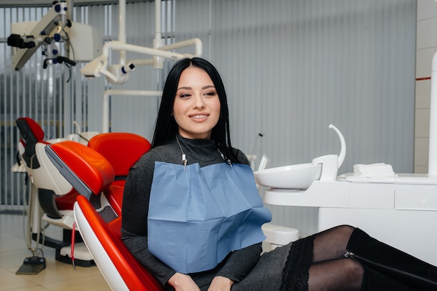 A girl patient of a dental clinic is sitting in a chair and smiling