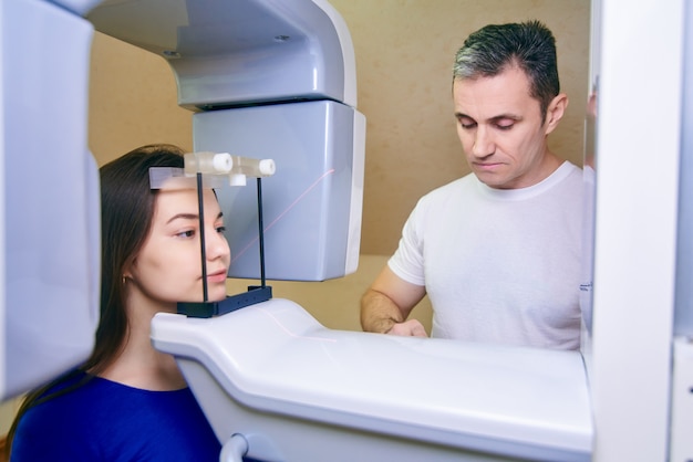 Girl-patient stands in a tomograph, a doctor near the control panel