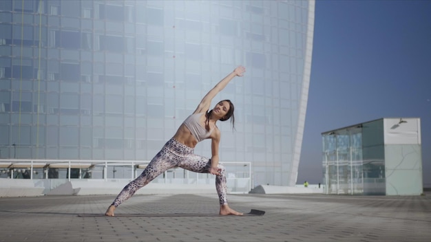 Girl performing yoga at street Woman doing extended side angle pose at street