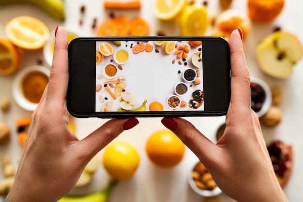 A girl photographs healthy food on a smartphone. Products for immunity. Top view.