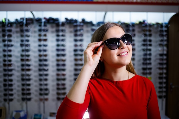 Girl picks up sunglasses. Eyeglasses shop. Vision correction. Glasses Stand