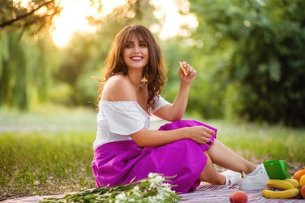 Girl at a picnic eating snacks and laughing