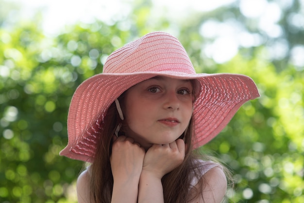 Girl in a pink hat and white dress. Girl 9 years old in the summer in the garden.