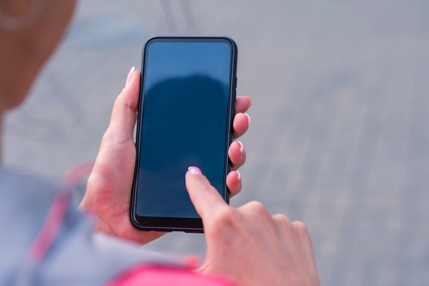 Girl in a pink jacket holds a smartphone mockup in hands. Mock-up Technology.