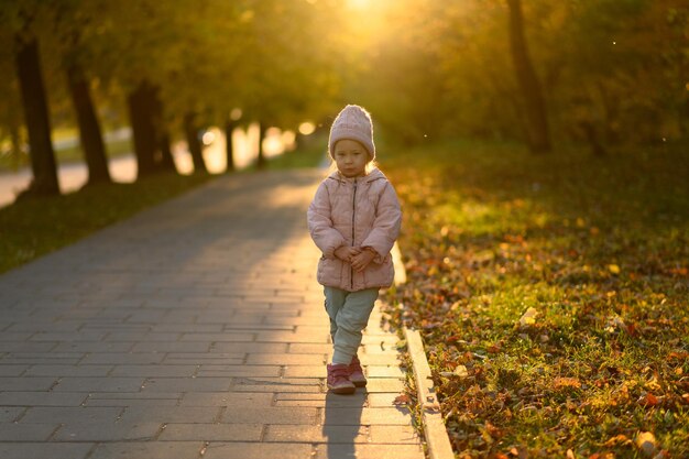 A girl in a pink jacket stands at sunset