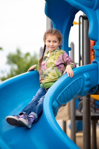 A girl on the playground She on the slide and has a fun Childhood Time with family Spring City