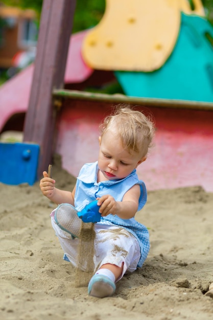 Girl playing with toys in the sandbox in the yard