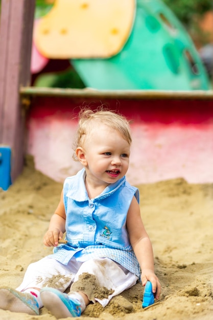 Girl playing with toys in the sandbox in the yard