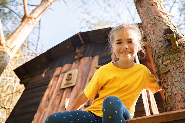 Girl plays in creative handmade treehouse in backyard summer activity happy childhood cottagecore