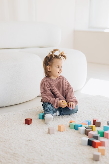 Girl plays toys in living room Montessori wooden toy folded pyramid Circle triangle rectangle wooden elements of children39s toys colored toy blue yellow red green