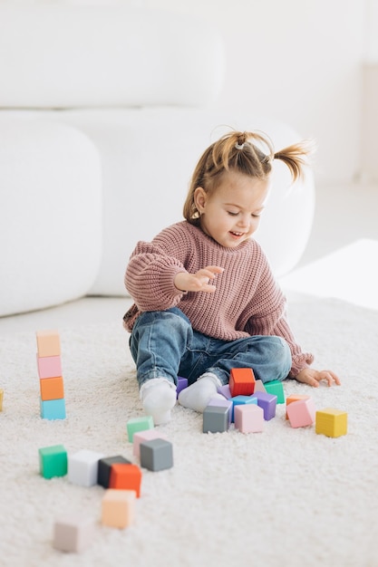 Girl plays toys in living room Montessori wooden toy folded pyramid Circle triangle rectangle wooden elements of children39s toys colored toy blue yellow red green