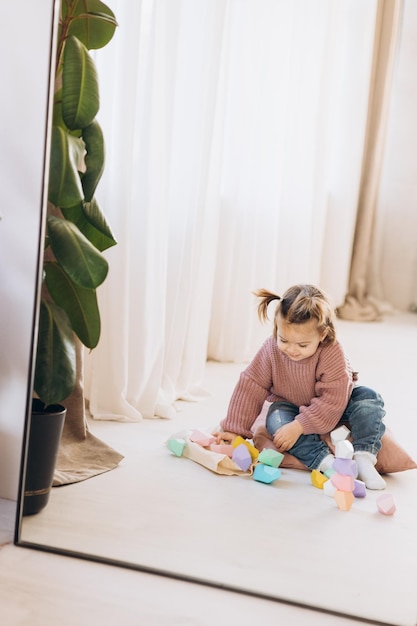 Girl plays toys in living room Montessori wooden toy folded pyramid Circle triangle rectangle wooden elements of children39s toys colored toy blue yellow red green