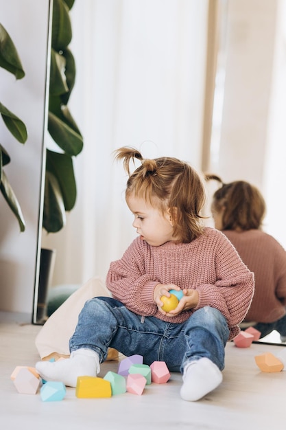 Girl plays toys in living room Montessori wooden toy folded pyramid Circle triangle rectangle wooden elements of children39s toys colored toy blue yellow red green