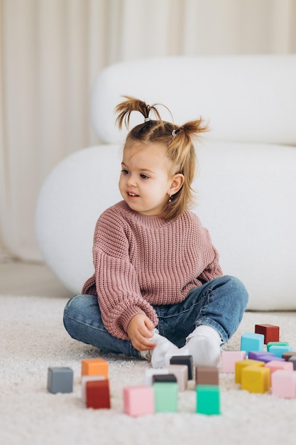 Girl plays toys in living room Montessori wooden toy folded pyramid Circle triangle rectangle wooden elements of children39s toys colored toy blue yellow red green