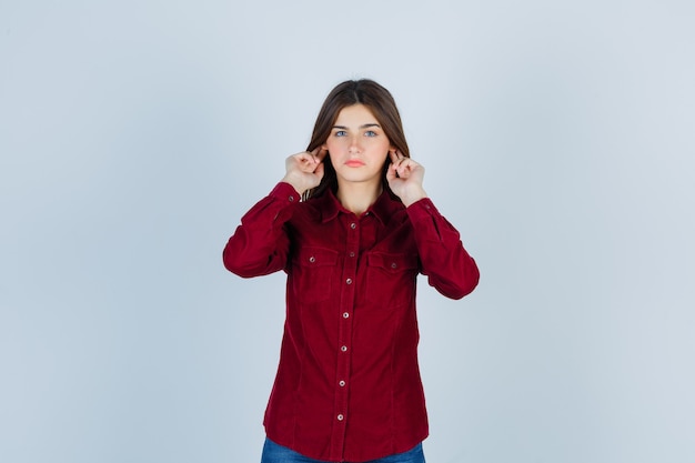 girl plugging ears with fingers in casual shirt and looking calm