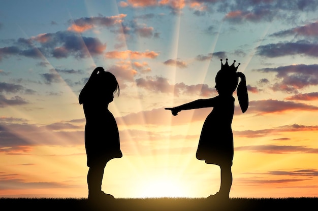 Girl points finger at another crying girl The concept of bullying among children and at school