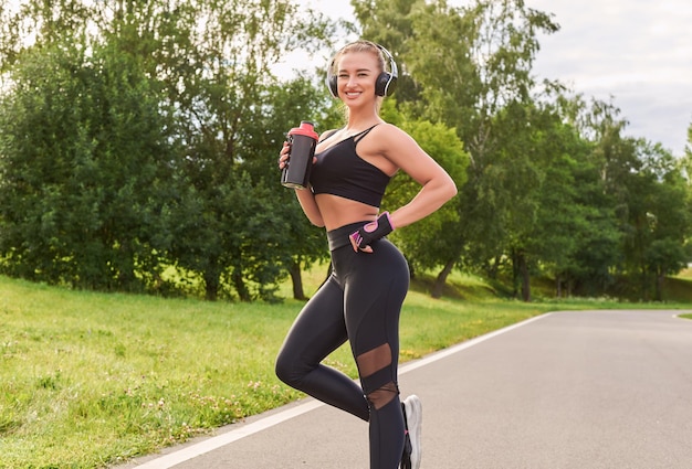 Girl posing with a sports nutrition shaker in the park The concept of a healthy lifestyle Sports Equipment Fitness style advertisement