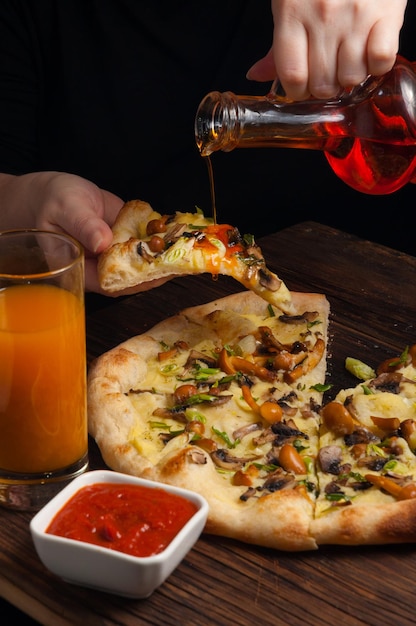 The girl pours spicy butter on the pizza with mushrooms concept vegetarianism