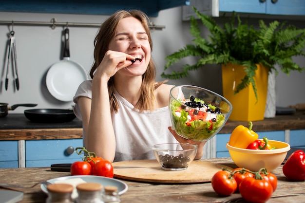 girl prepares a vegetarian salad in the kitchen