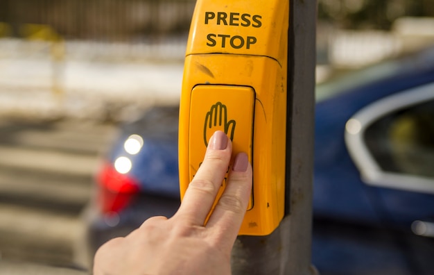 Girl press sign stop on cross section to walk over the city street.