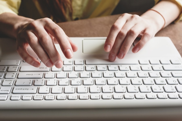 The girl prints on a white computer. Closeup of hands on the keyboard of a computer.