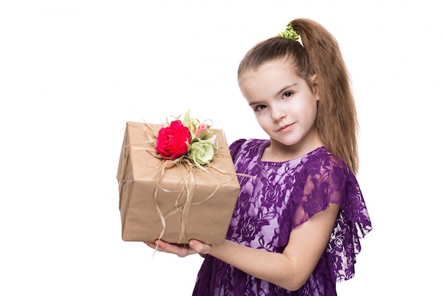 Girl in purple lace dress holding a box with a gift decorated with flowers.