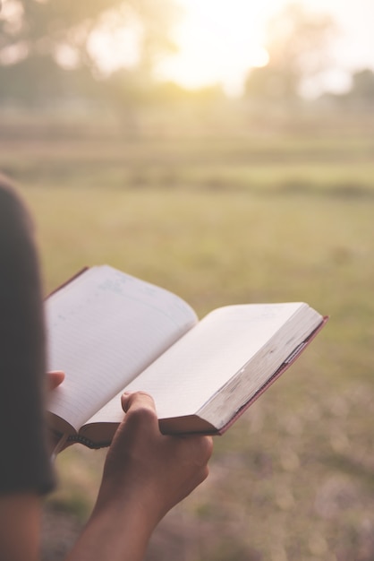 Girl reading a book on countryside background. 