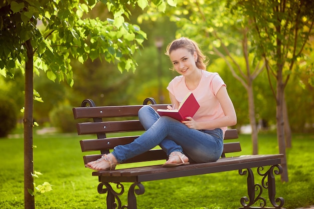 Girl reading a notebook sitting on a bench in the Park