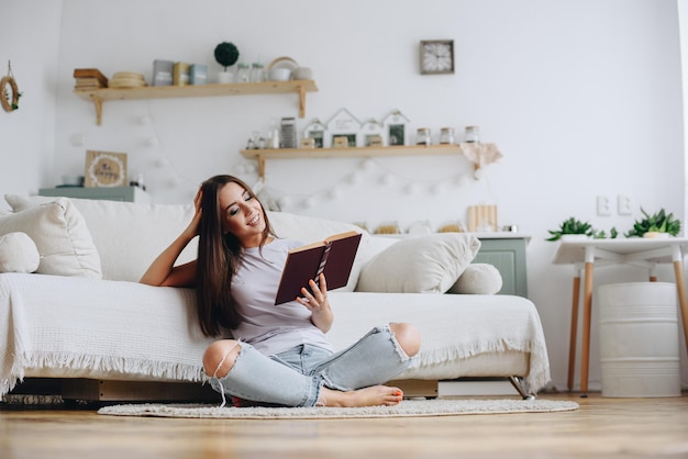 The girl reads a funny book a novel at home near the sofa during the day Selftaught