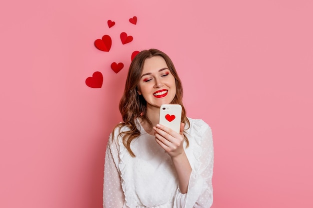 The girl reads love sms smiling on a pink background valentine's day congratulations