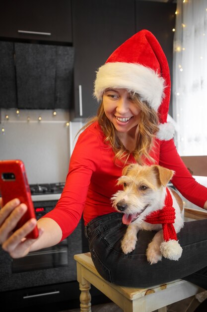 Girl in red clothes and jack russell terrier look into a smartphone in the kitchen