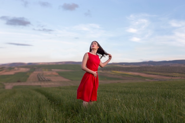 Girl in red dress in the field at sunset