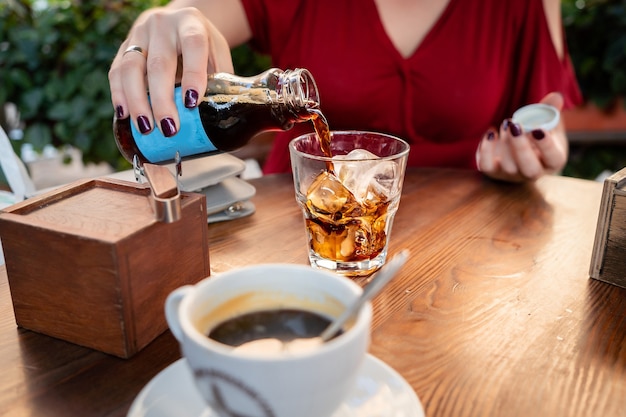 girl in the red dress pours a drink cola coffee ice