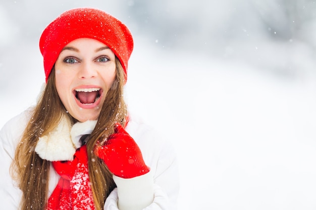 Girl in red hat and scarf looks in the camera and open her mouth