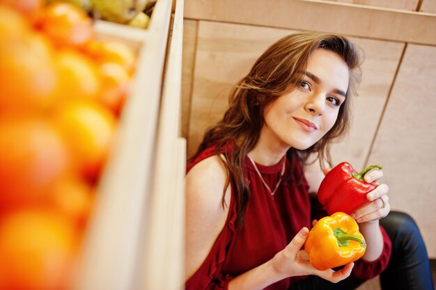 Girl in red holding two peppers on fruits store