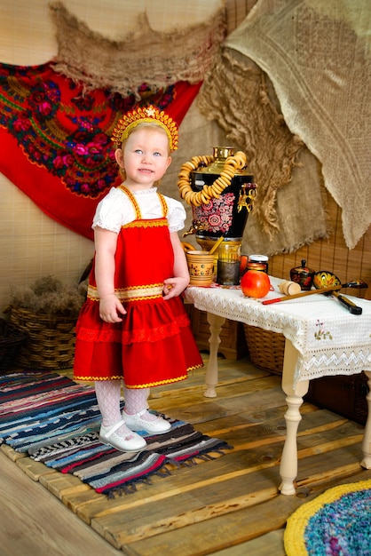 A girl in a red national costume near a table with a samovar and steering wheels Pancake day