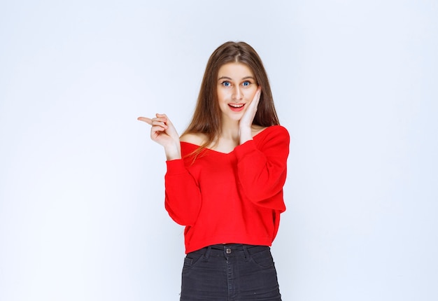 Girl in red shirt showing something on the left side. 