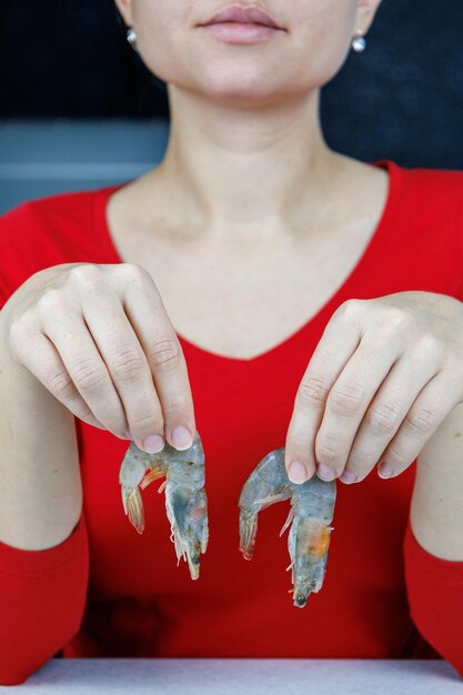 A girl in a red sweater holds two tiger shrimps in her hands Seafood