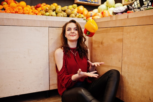 Girl in red throw peppers on fruits store