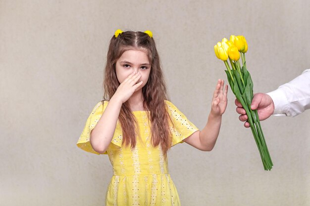 A girl refuses a bouquet of spring flowers to prevent allergy symptoms