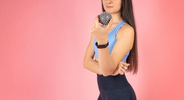 The girl relaxes the muscles with the help of a massage ball Woman holding a gray massage ball over the muscles of her arms warming them up and preparing them for training Healthy lifestyle concept