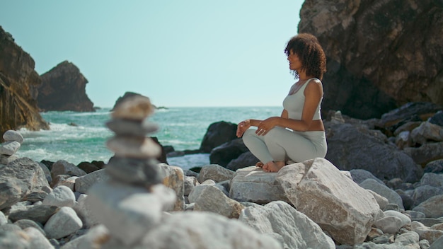 Girl relaxing sitting lotus pose on stone Ursa beach Woman meditating on nature